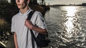 Jongen met rugzak langs het water