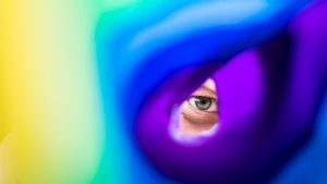 oog kijkt door opgerolde regenboogvlag
