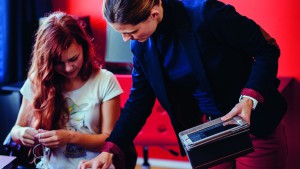 De leraar geeft uitleg aan een leerling die werkt met een tablet in de klas