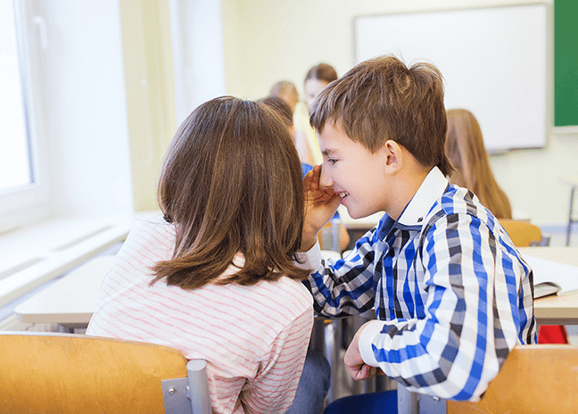 Twee vrienden fluisteren met elkaar in de klas