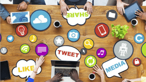 Handen rond een tafel die tokkelen op laptops en tablets om social media te gebruiken.
