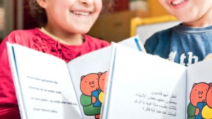 Kinderen tonen boekjes met Nederlandse en Arabische tekst