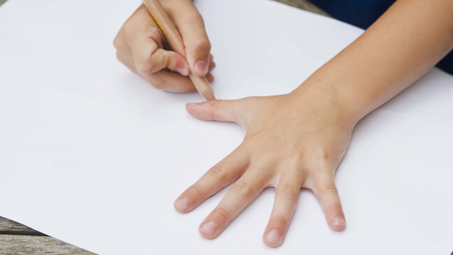 leerling tekent hand op blad papier