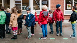 Leerlingen lagere school staan in de rij op groene stippen