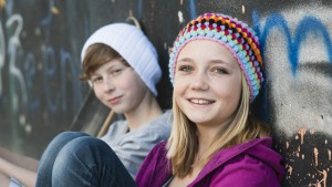 Meisje en jongen zitten tegen muur