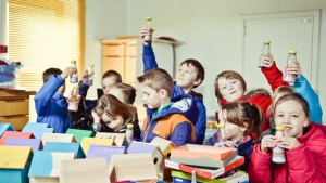 kinderen vullen flesjes met gekleurd zand