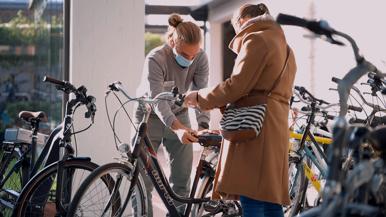 Man helpt vrouw met zadel van fiets