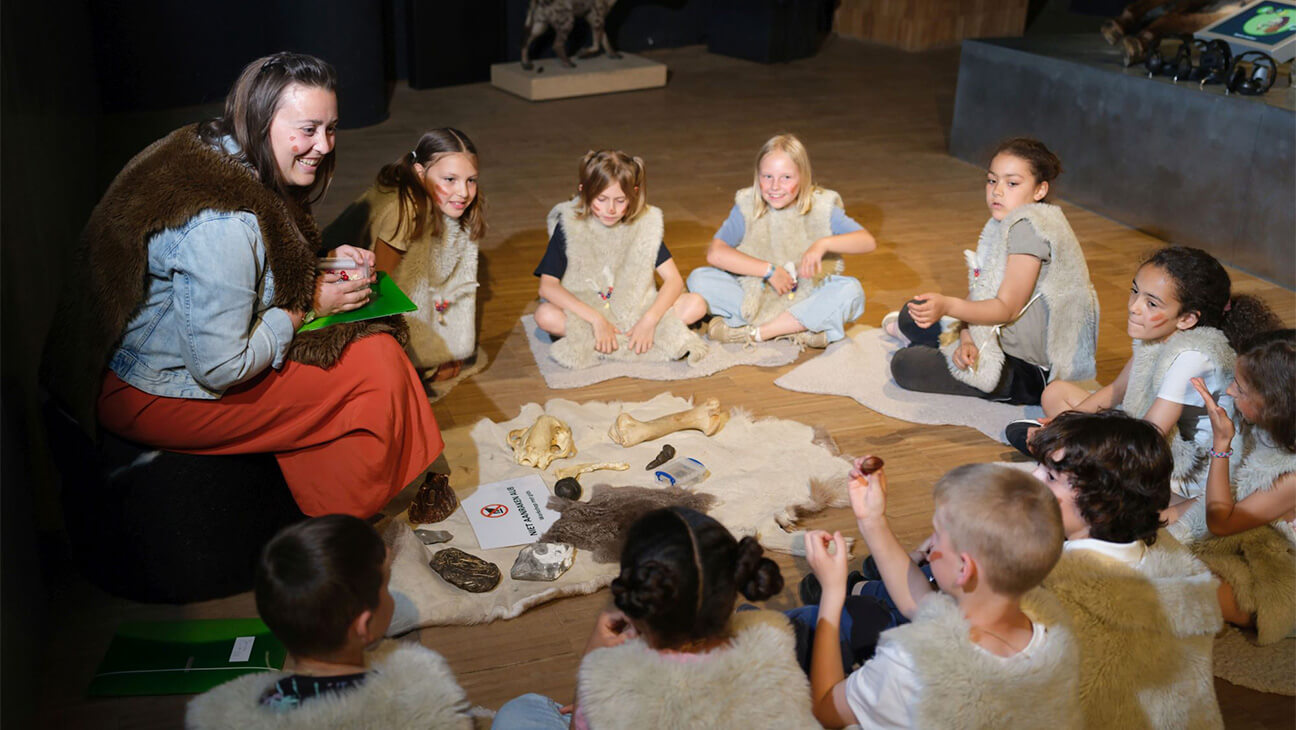 Kinderen in een kring verkleed als oude romeinen in het Gallo-Romeins Museum