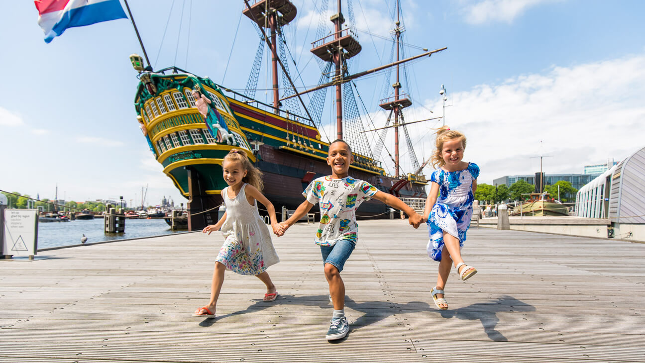 Kinderen wandelen op kade voor het Scheepvaartmuseum in Amsterdam