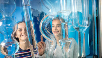 2 meisjes kijken enthousiast naar buizen met water