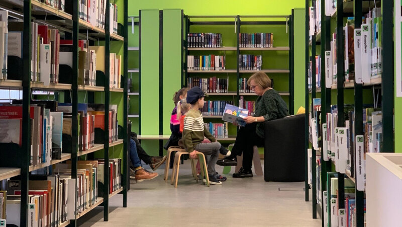 Mevrouw leest voor aan kinderen in Bibliotheek van Bocholt