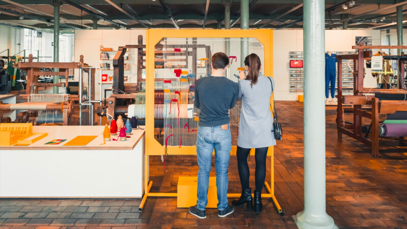 2 mensen aan een weefgetouw in het industriemuseum