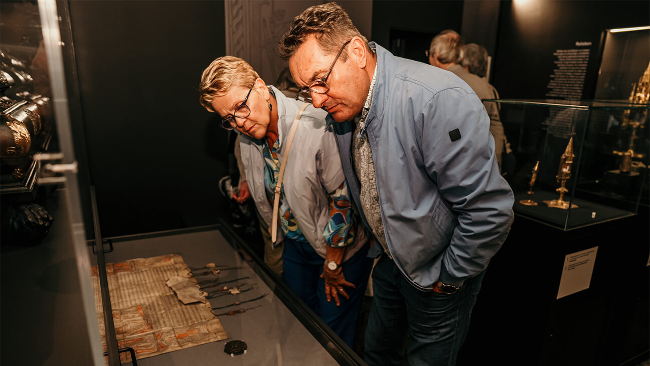  Bezoekers kijken naar oud document in De Schatkamer van Sint-Catharina