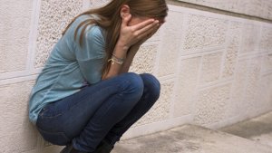 meisjes zit gehurkt met hoofd in handen