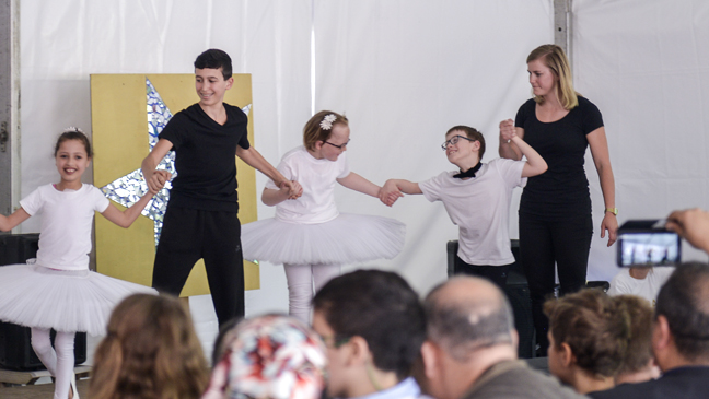 Leraren en leerlingen dansen op een podium tijdens schoolfeest