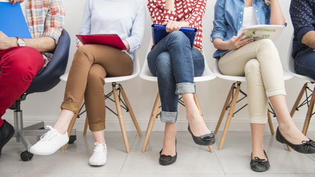 sollicitanten zitten op een rij stoelen te wachten op sollicitatiegesprek