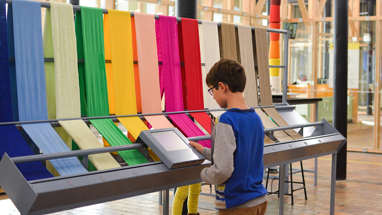 Jongen bij verschillende kleuren stof in Texture, het Museum over Leie en Vlas