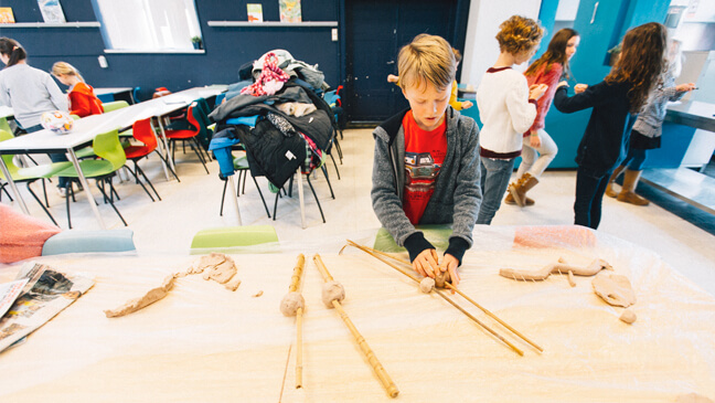 jongen maakt skelet met klei en hout