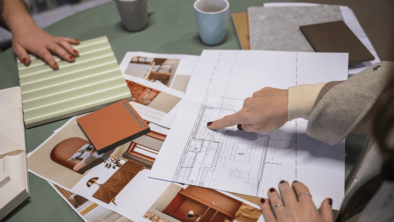 Vrouw kijkt naar bouwplannen met een kleurstaal van Paintfactory