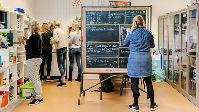 leraar aan een planningsbord, toont dat jobcrafting of een jobruilbeurs passen in het personeelsbeleid van een school