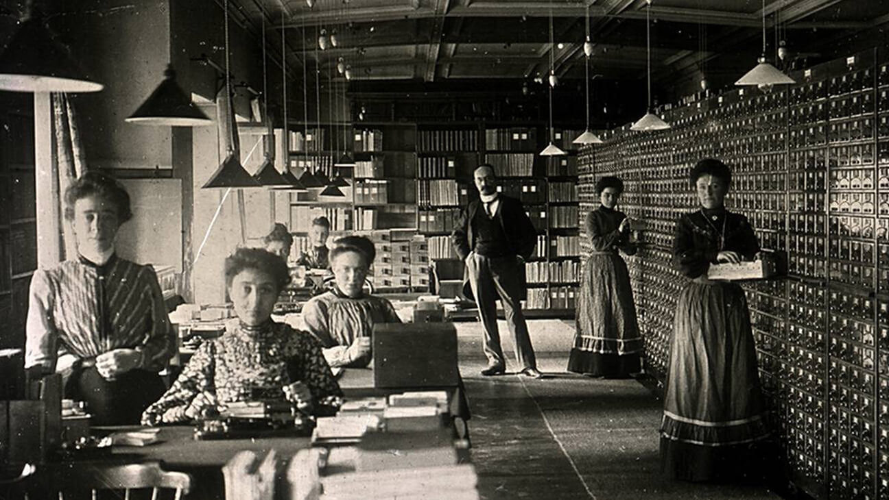 Oude foto waar werknemers van Mundaneum papieren sorteren in houten bakjes