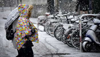 iemand met bonte mantel steekt straat over in de sneeuw
