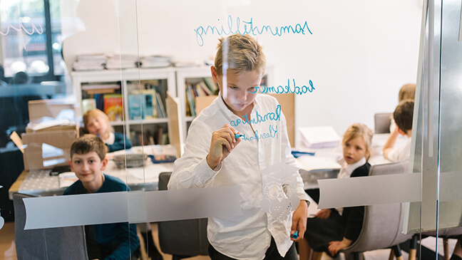 Jongen schrijft iets op bord in de basisschool Mondomio