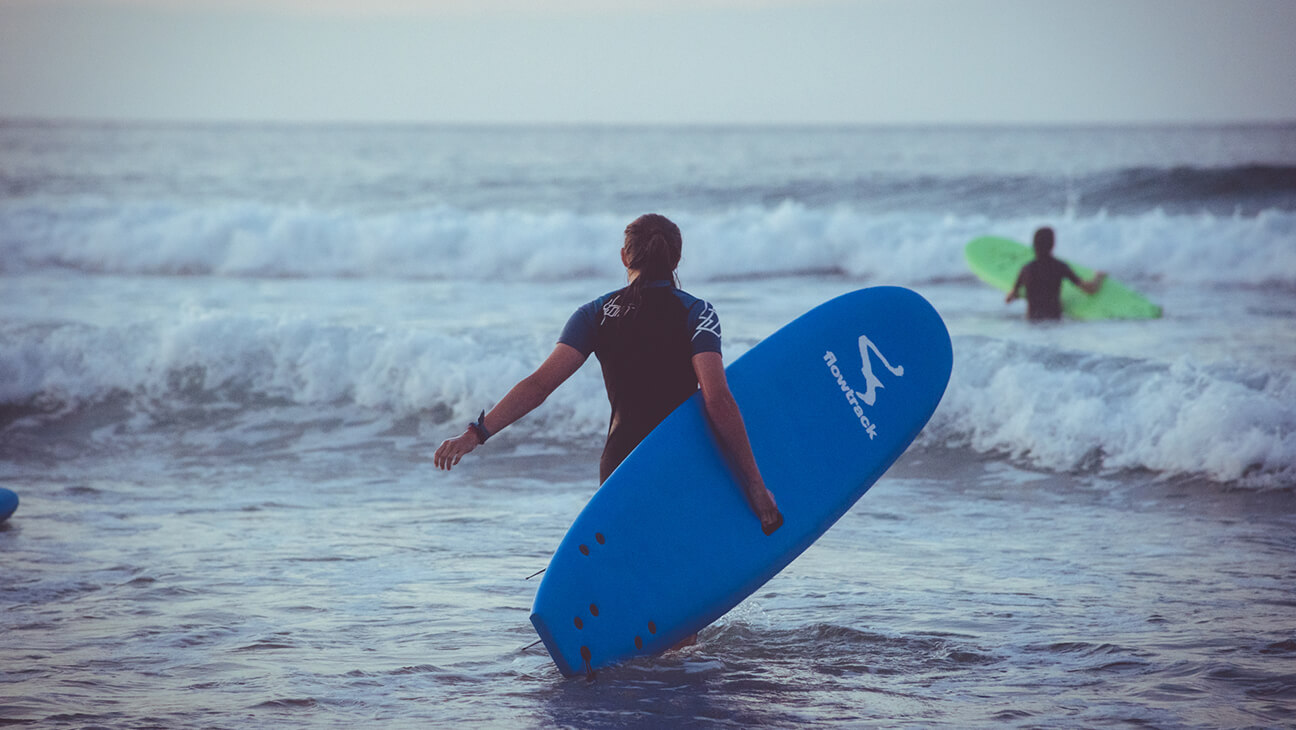 Jongeren met surfboard tijdens surfvakantie met Flowtrack