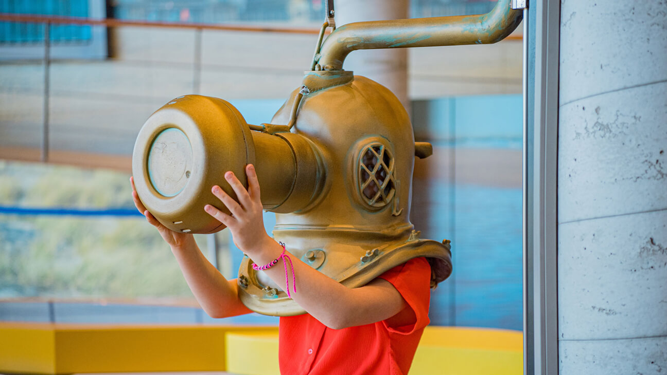 Meisje test duikerhelm in Bezoekerscentrum Duinpanne