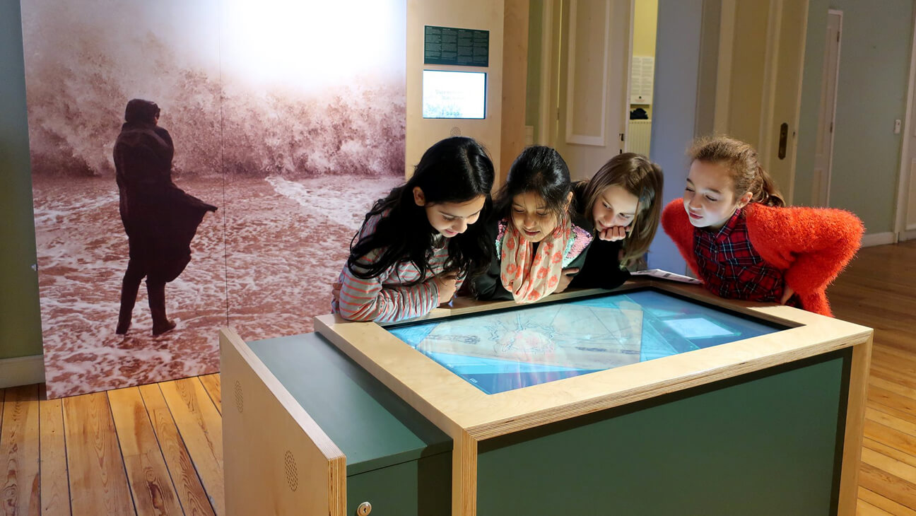 Kinderen kijken naar een interactief scherm van het stadsmuseum van Oostende