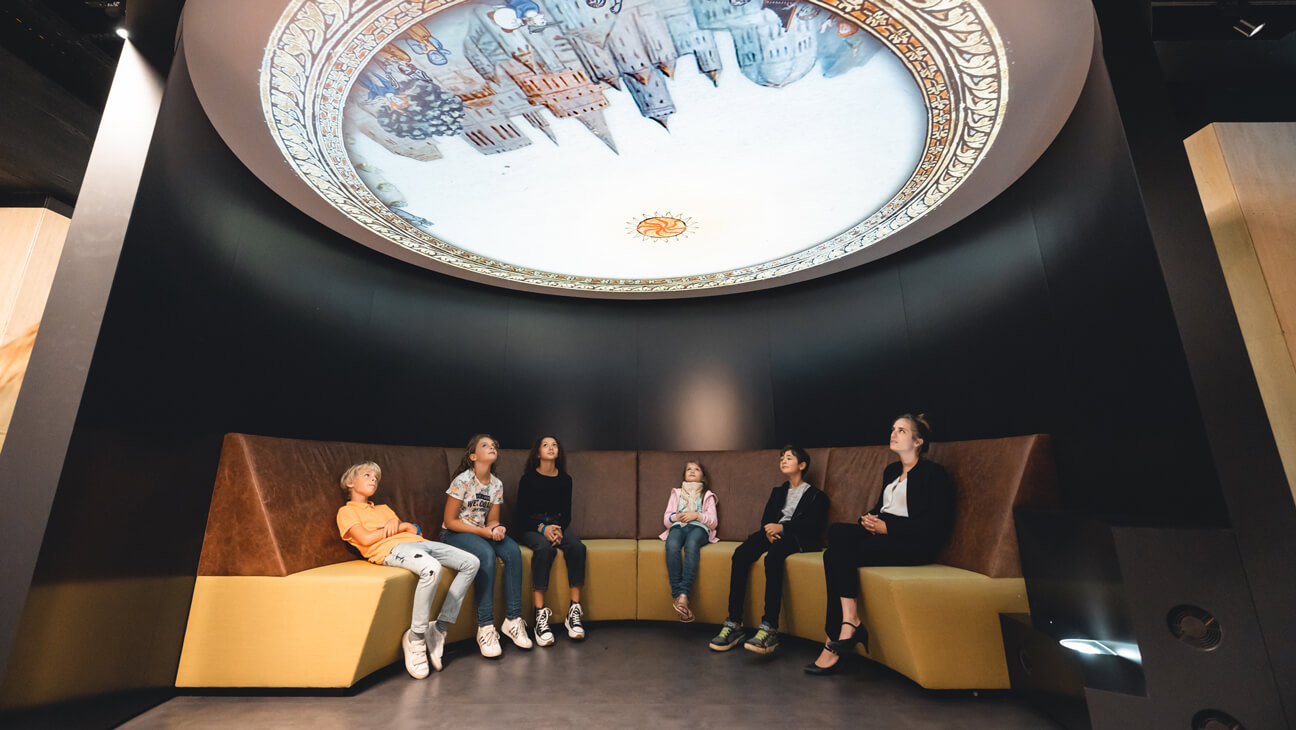 Bezoekers kijken naar projectie op plafond in KBR museum