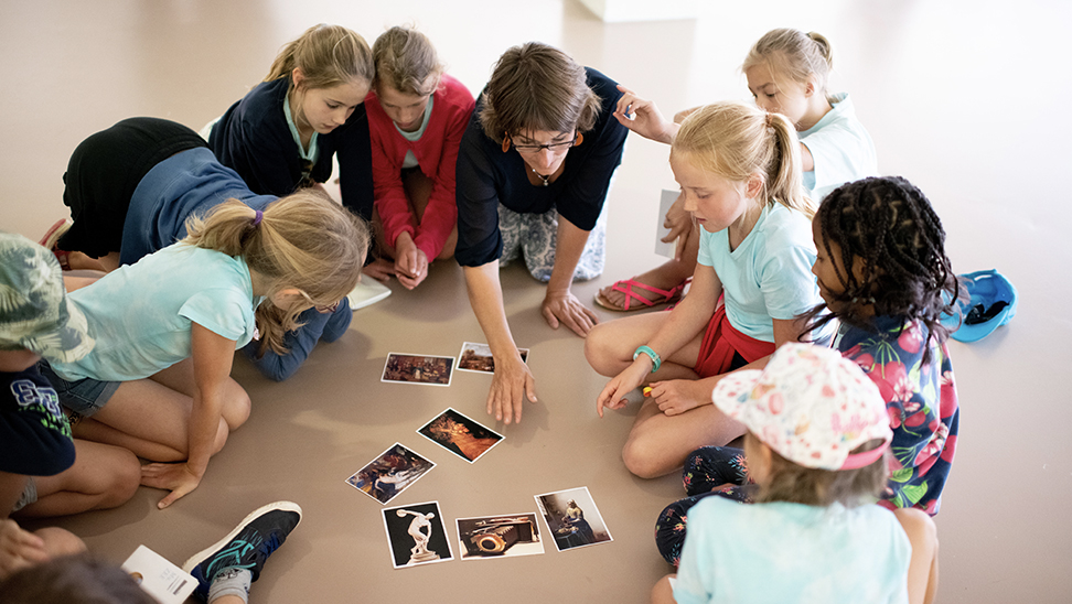 kinderen en leerkracht bekijken kunstige foto's