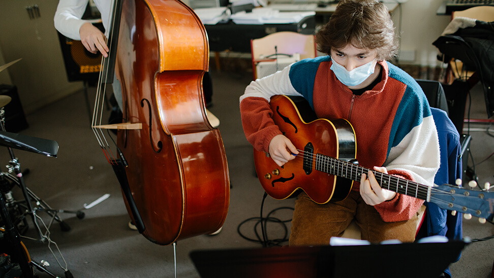 Jongen met een gitaar in de kunsthumaniora