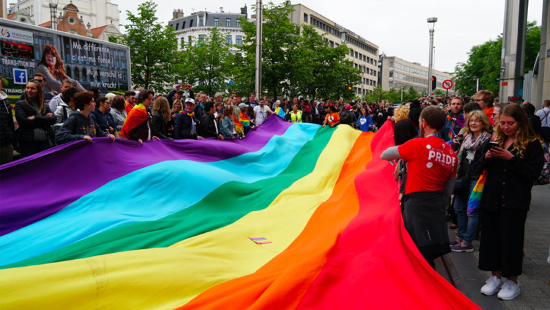 Foto van mensen bij een regenboogvlag tijdens een optocht