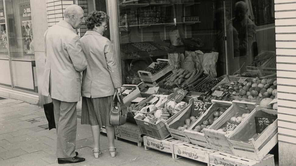 oude foto van koppel voor etalage van buurtwinkel