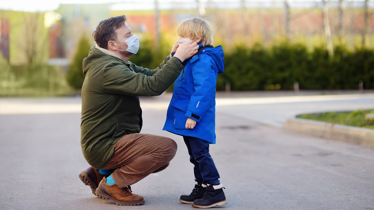 Vader doet mondmasker aan bij kind