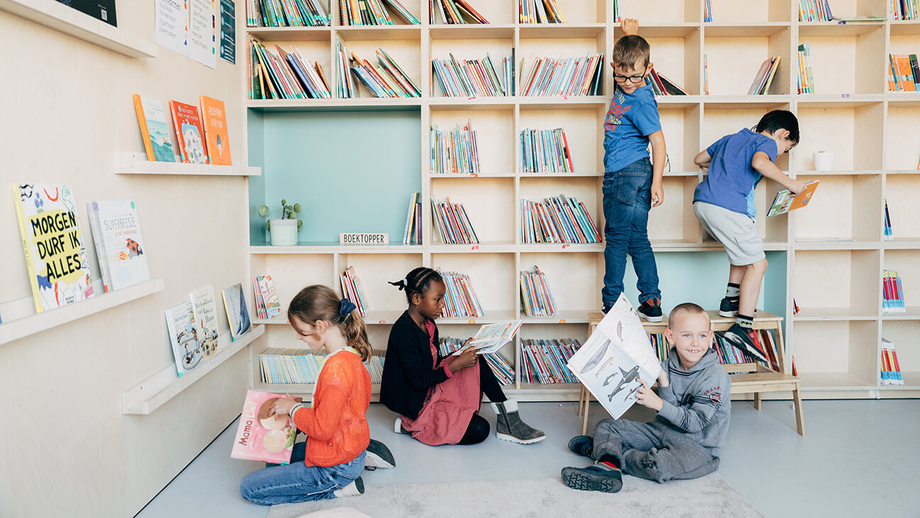Kinderen lezen boeken bij een boekenkast