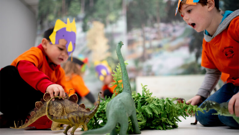 Jongens met een dinomasker spelen met dinosaurussen