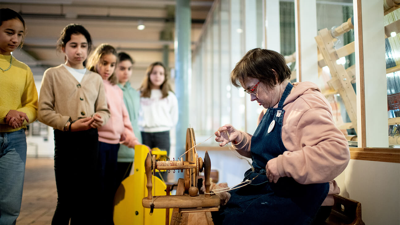 Vrouw werkt aan een spinnewiel in het industriemuseum in Gent