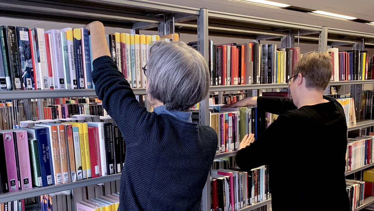 Medewerkers ruime rekken met boeken op in bibliotheek Bree