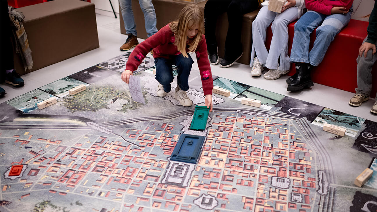 Leerling legt gebouw op groot spelbord in Gallo-Romeins museum
