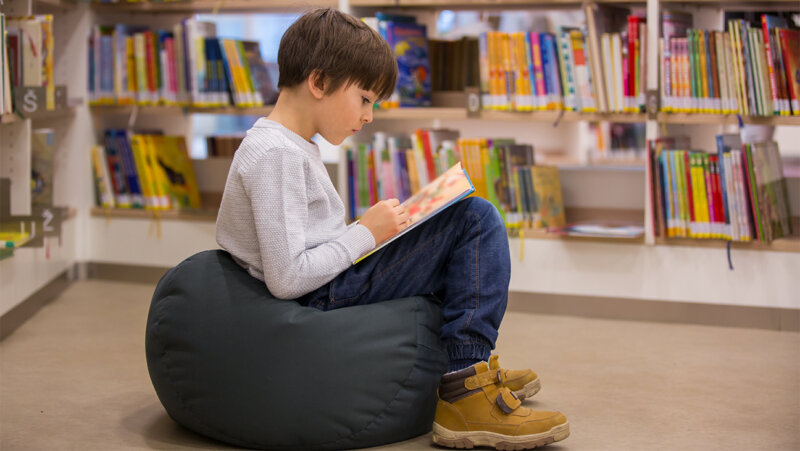 Jongen leest boek in de bibliotheek
