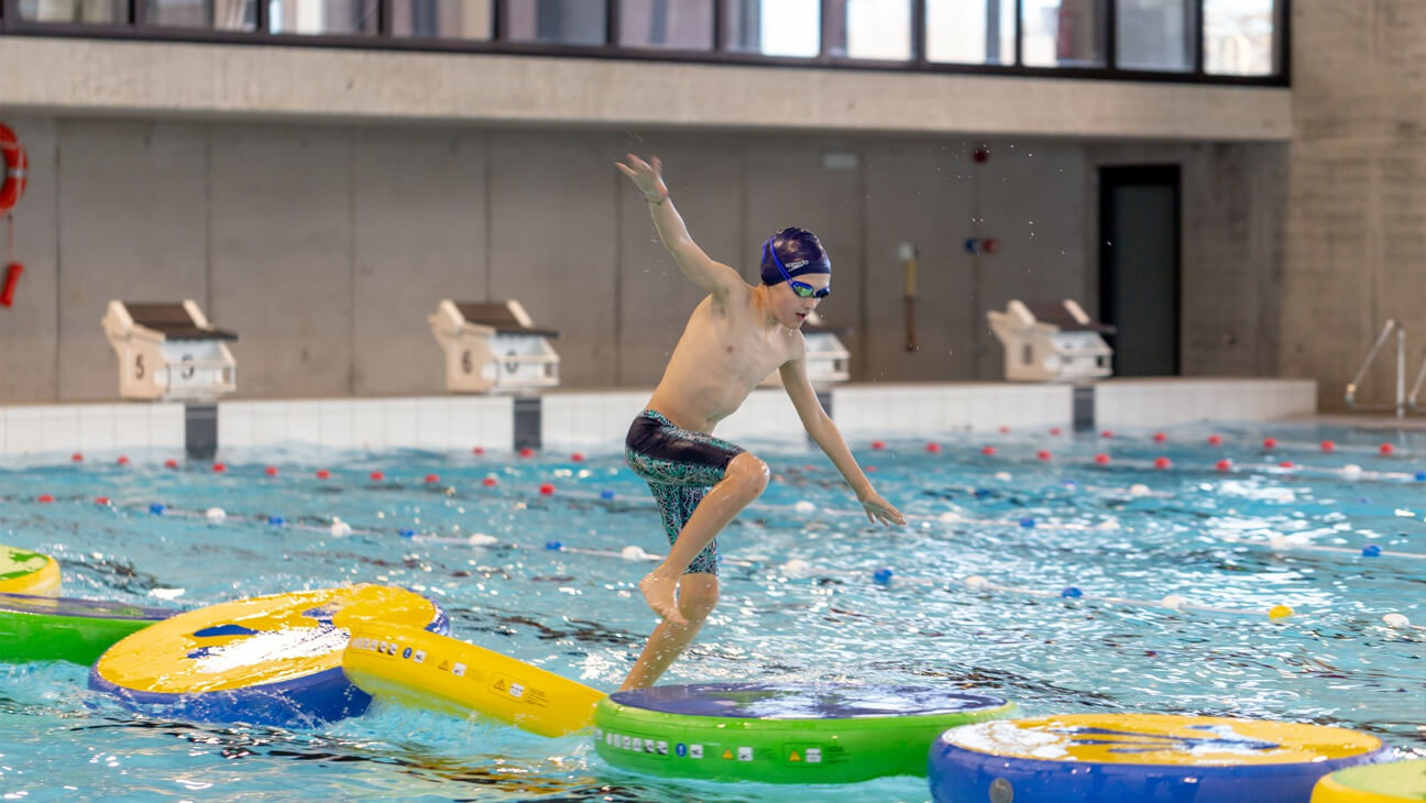 Kind op een obstakelparcours in een zwembad van Lago