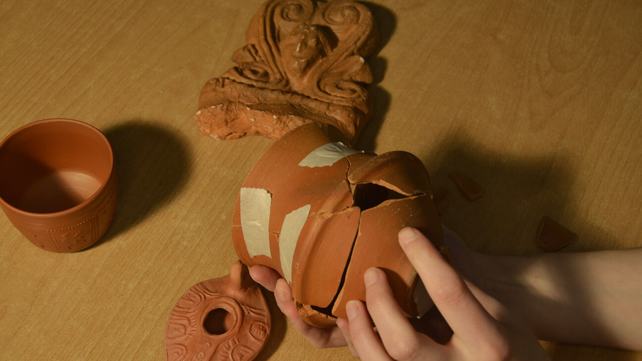 Hand lijmt een oude kruik aan elkaar