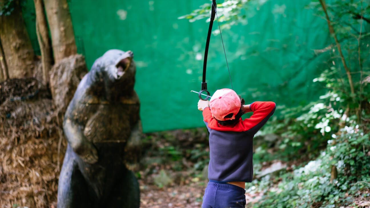 Jongen schiet met pijl en boog naar beer