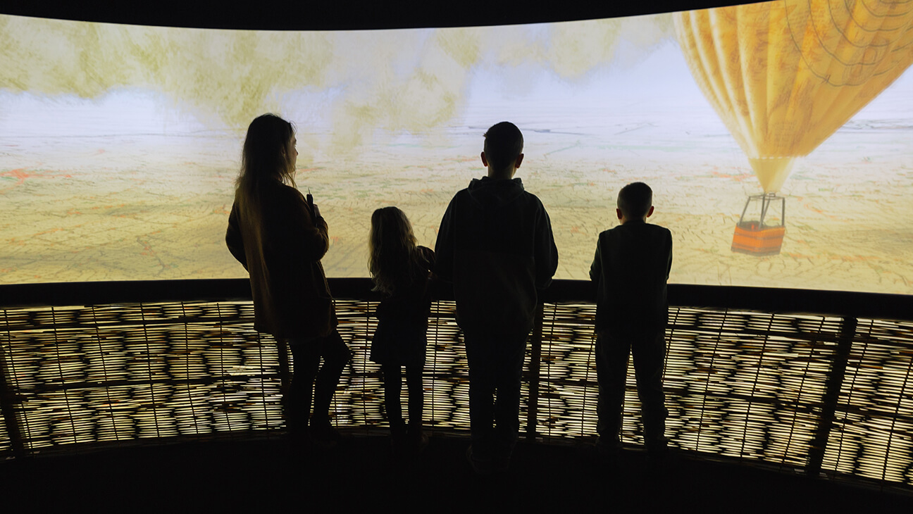Kinderen kijken naar een groot scherm met een luchtballon