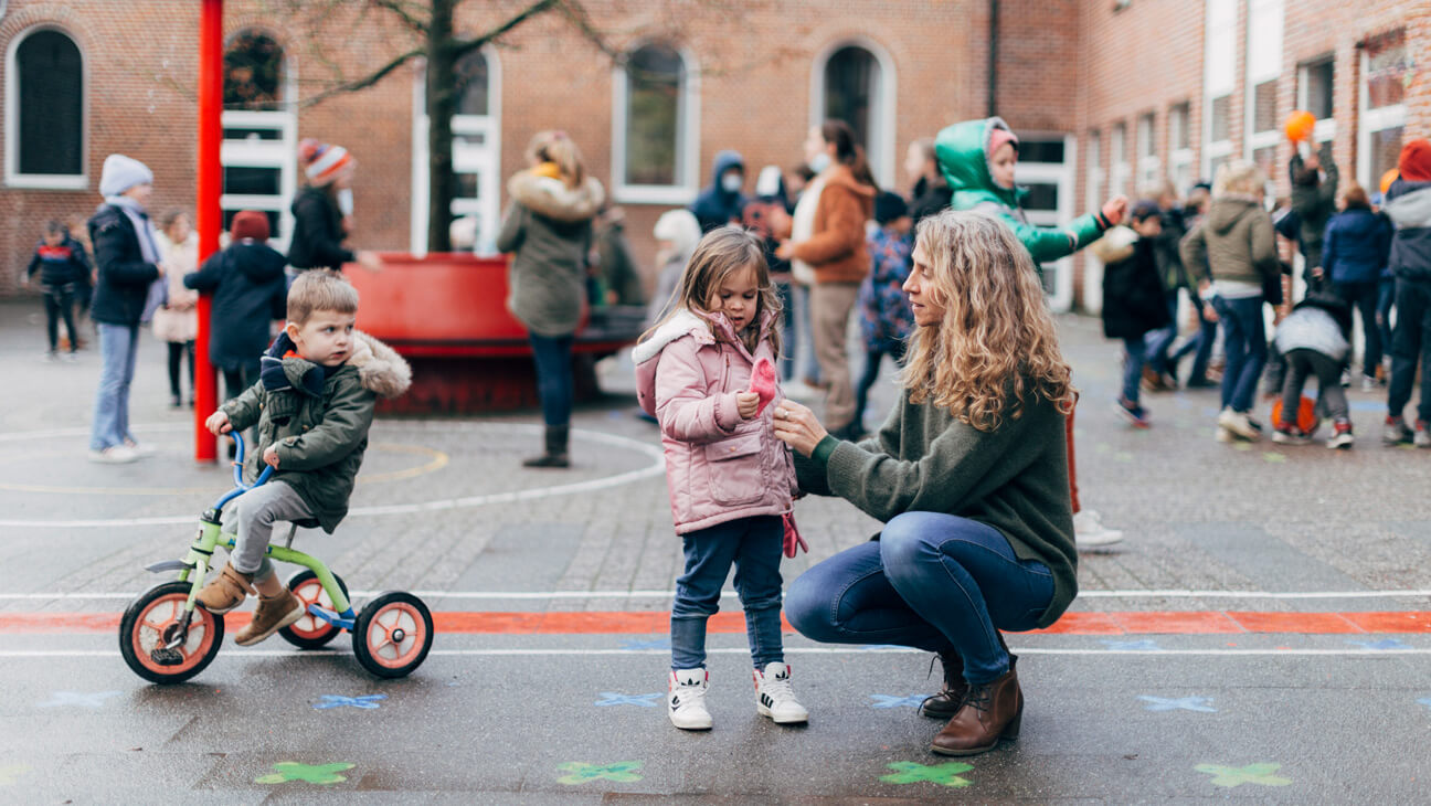 directeur Marie Van Driessche met kleuters op de speelplaats