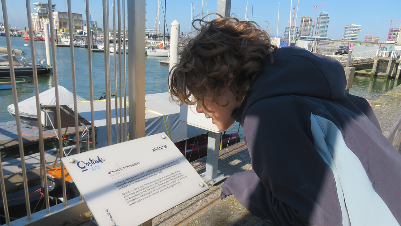 Man kijkt naar een infobord over Oostende