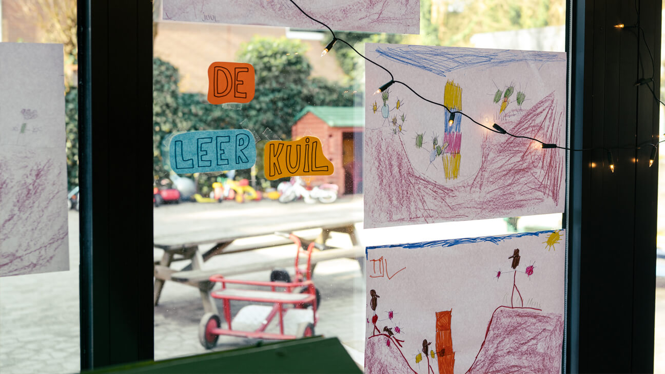 tekeningen van de leerkuil hangen tegen een klasraam