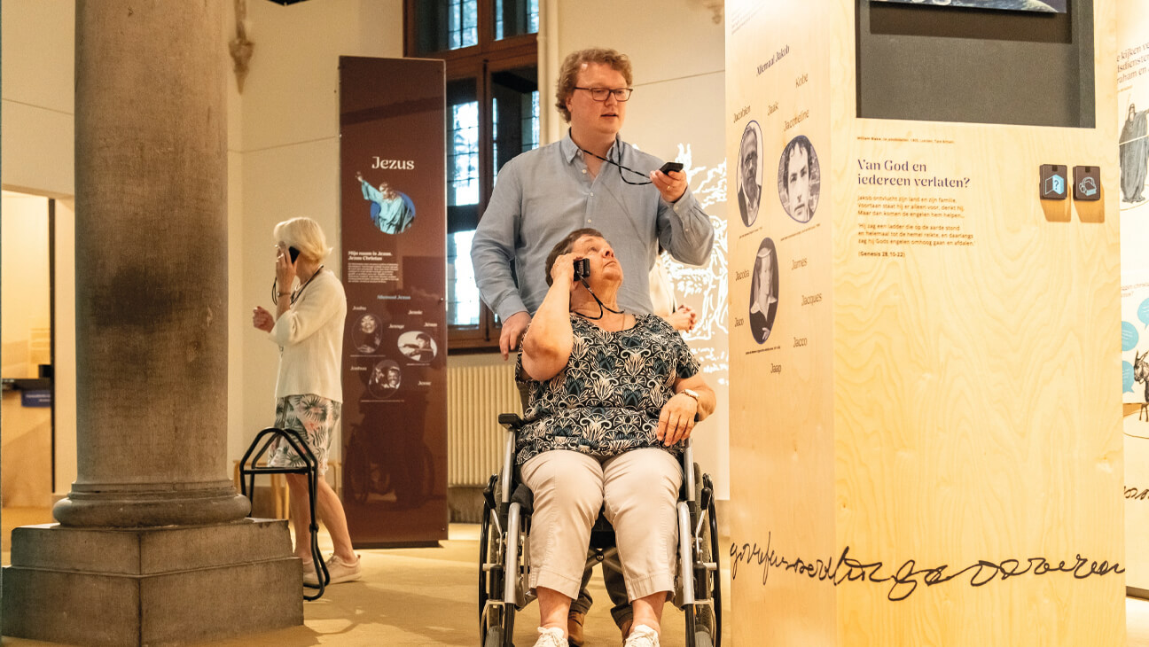 Bezoeker duwt iemand met een rolstoel op de expo 'Biblia'